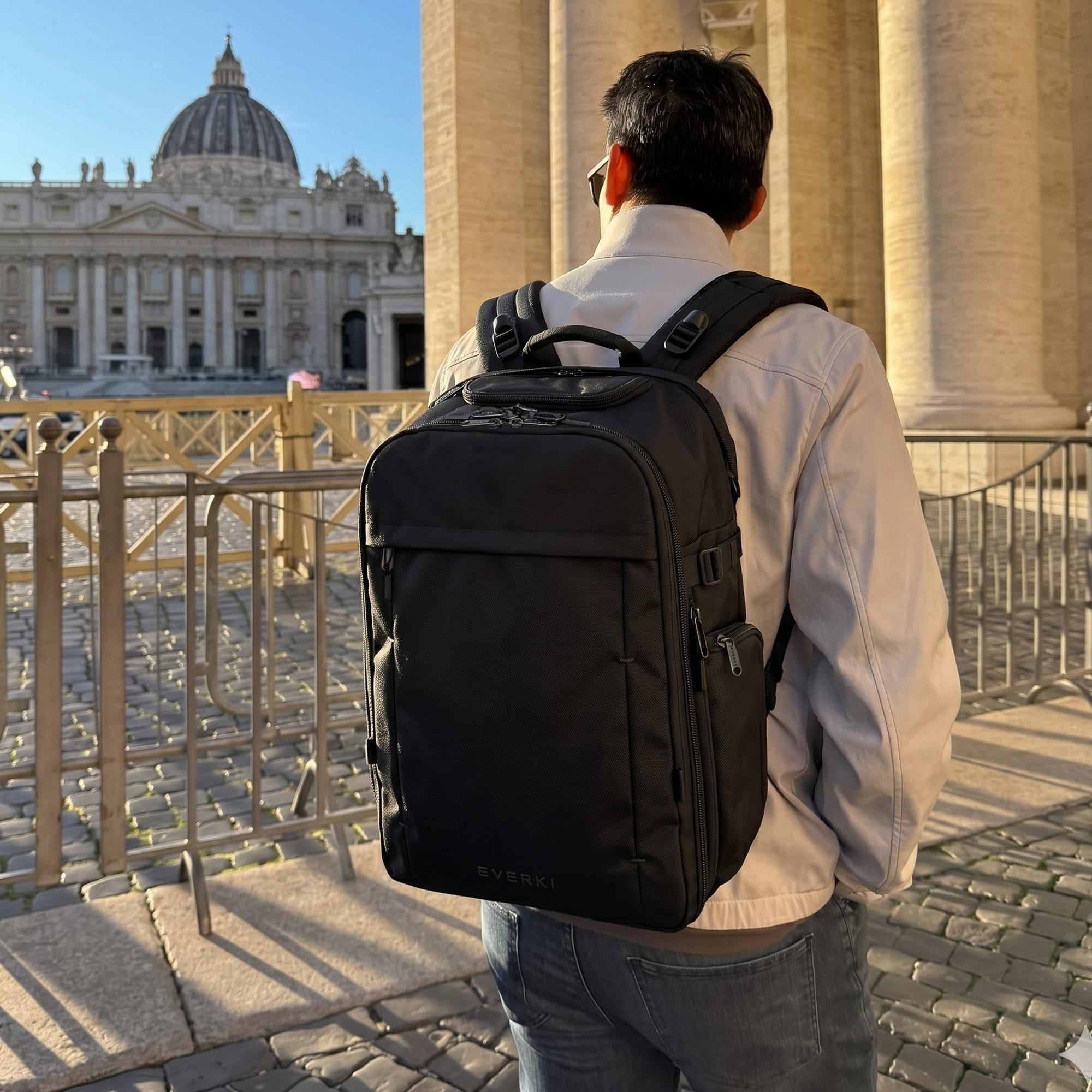 A traveler wearing the EVERKI ONE backpack in a sunlit city square