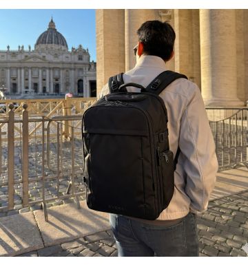 A traveler wearing the EVERKI ONE backpack in a sunlit city square
